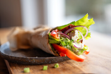 Tortilla wrap with fresh vegatables and fried chicken meat on a plate. Background concept with for...