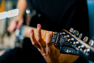 musician with electric guitar in recording studio plays musical instrument presses fingers on strings close-up