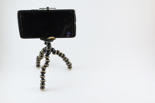 flexible tripod, black gorilla pod with black mobile phone on white background isolated
