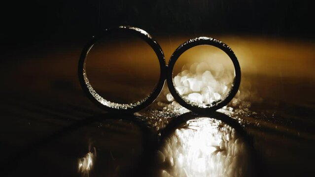 Two rings stand under splashes of water in a beautiful background light. Shooting in slow motion