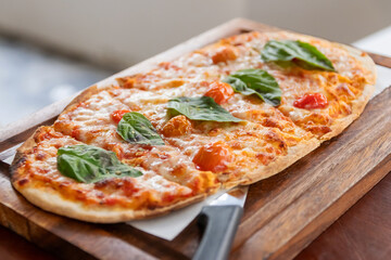 Italian pizza margherita with cheese, tomato sauce and basil served on the wooden board.