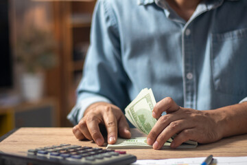 A man meticulously counts dollar bills, reflecting the concept of currency management in...