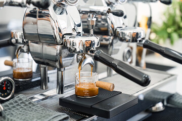 Espresso machine making hot coffee into dosing cup in coffee shop