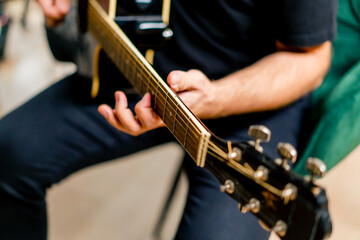 musician with electric guitar in recording studio plays musical instrument presses fingers on strings close-up
