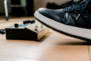 musician's male foot pressing bass drum pedal or bass electric guitar in recording studio close-up