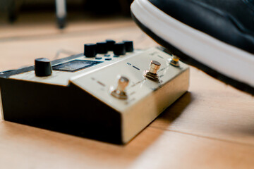 musician's male foot pressing bass drum pedal or bass electric guitar in recording studio close-up