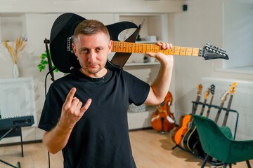 portrait of a brutal rock performer with an electric guitar in a recording studio before a...