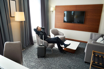 Man sits with his arms outstretched in a hotel room