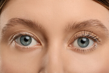 Woman showing difference in eyelashes length after mascara applying, closeup