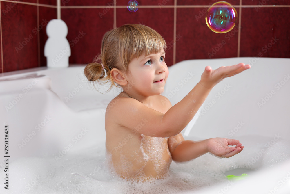 Wall mural little girl having fun in bathtub at home