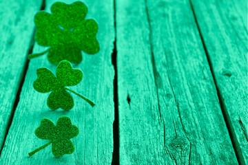 St. Patrick's day. Decorative clover leaves on green wooden background, space for text