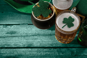 St. Patrick's day. Beer, leprechaun pot of gold and decorative clover leaves on green wooden table, above view. Space for text