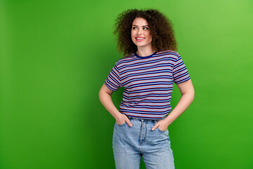 Photo of lovely positive person put hands pockets look interested empty space isolated on green...