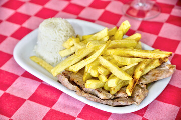 Grilled pork chops at a restaurant, served with rice and golden fries. A delectable dish capturing the essence of dining out in style.