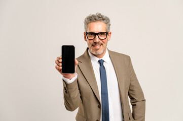 A senior business executive confidently showcases an empty smartphone screen, ideal for advertising. Concept of technology trends and digital communication in the professional world