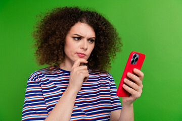 Photo of pensive minded girl hand touch chin use smart phone contemplate isolated on green color...