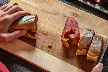 Close-up of hands cutting pink salmon into plastics. High angle shot. Process of cutting sea fish....