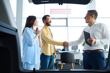 Manager greets clients at a car dealership