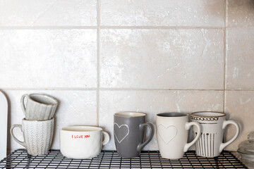 Gray and white cups with hearts and the inscription - I love you on a shelf in the kitchen against...