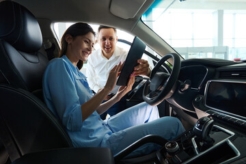 Consultant at car dealership presents documents for new car to customer