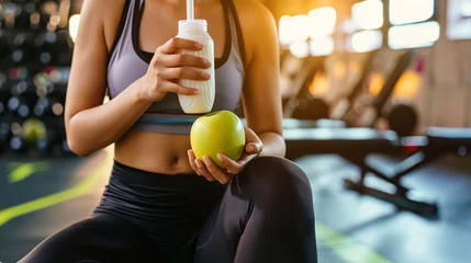 Tuinposter Woman exercise workout in gym fitness breaking relax holding apple fruit and protein shake bottle after training sport © Mas