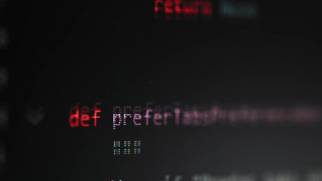 Close-up shot of the screen with scrolling programming code on a dark background.