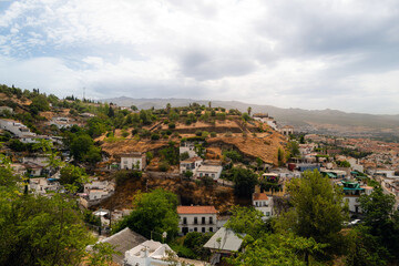 Fototapeta na wymiar Granada, Spain, panoramic view of the city with mountains in background during hazy day. white buildings and trees, residential and commercial buildings. copy space no people, logos.
