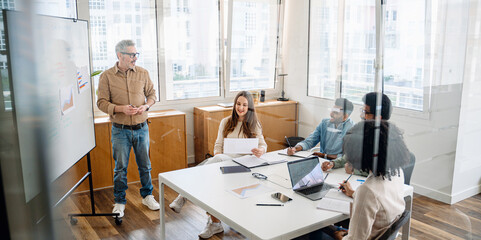 A knowledgeable mature leader facilitates a strategic discussion with a multicultural team, a calm and productive atmosphere, ideal for innovative thinking and inclusive decision-making