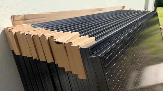 Close-up new solar panels with protective cardboard corners, ready for installation. Renewable energy technology, green living, and the implementation of solar power in residential areas.