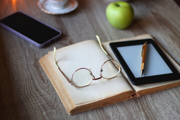 Vintage books, e-reader, pen, reading glasses, phone, cup of tea or coffee, bowl of cookies, green...