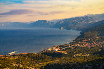Coastal village of Cala Gonone in Sardinia during sunset, photographed from above with surrounding...