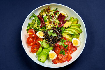 Bowl with salmon, quinoa and avocado on a blue background