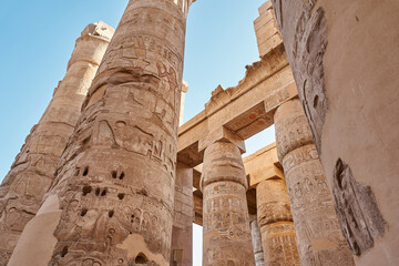 Different hieroglyphs on the walls and columns in the Karnak temple. Columns and blue sky in the...
