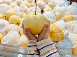Kids hand holding pear fruit at market