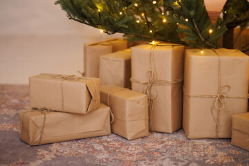 Many gifts under the Christmas tree wrapped in craft paper. High quality photo
