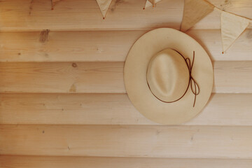 A light-colored straw beach hat hangs on the wooden wall, creating a summer vacation atmosphere....