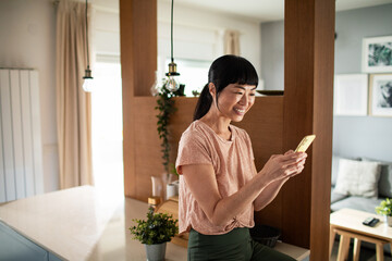 Smiling young woman with a smartphone at home