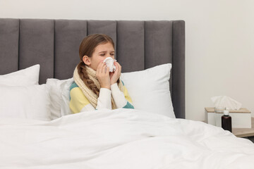 Sick girl with tissue coughing on bed at home