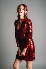 Mini sequin dress with glitter in maroon. Long sleeve outfit with deep sexy v neckline. Beautiful young woman in a sparkle gown; glamour female look for an event. Valentine's day look. Woman's fashion