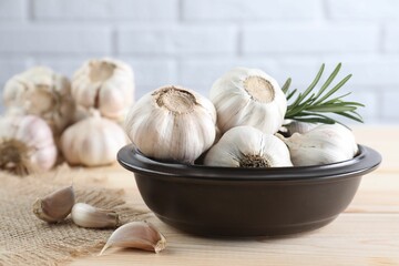 Fresh raw garlic and rosemary on wooden table, closeup