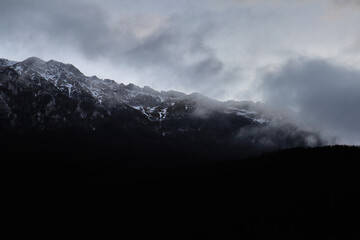 Primo piano di una montagna immersa da nuvole e un po' di neve