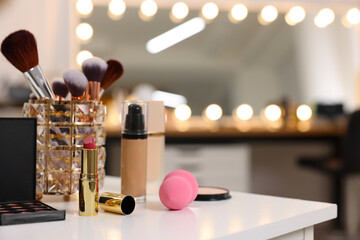 Different cosmetic products on white table in makeup room, space for text