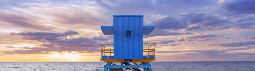  Vibrant, pastel view of lifeguard tower at sunrise colorful painted under bright blue sky on South Beach, Miami, Florida.