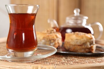 Traditional Turkish tea in glass on wicker table, closeup. Space for text