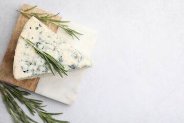 Tasty blue cheese with rosemary on light table, flat lay. Space for text