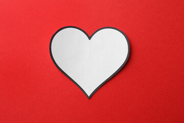White paper heart on red background, top view