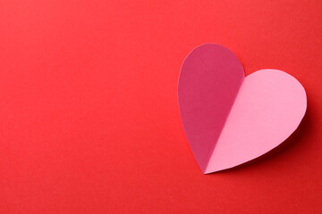 Pink paper heart on red background, top view. Space for text