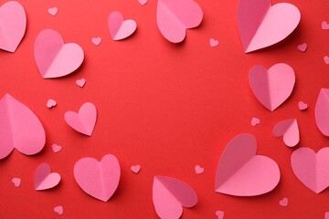 Frame of pink paper hearts on red background, flat lay. Space for text