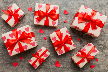 Top view photo of valentine day decorations gift box with red ribbon bow on colored background. Holiday gift boxes with top view