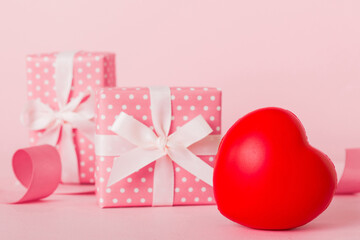 gift box with red bow and red heart on colored background. Perspective view. Flat lay